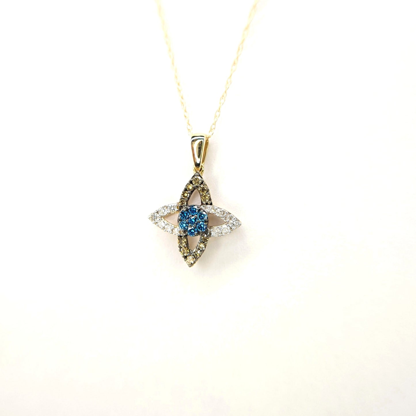 A gold chain displays a four petal flower-shaped diamond pendant. Two pendants show white diamonds and two pendants show cognac diamonds. All four connect featuring a central blue stone.